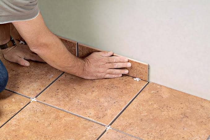 Installer setting a tile along the wall with spacers