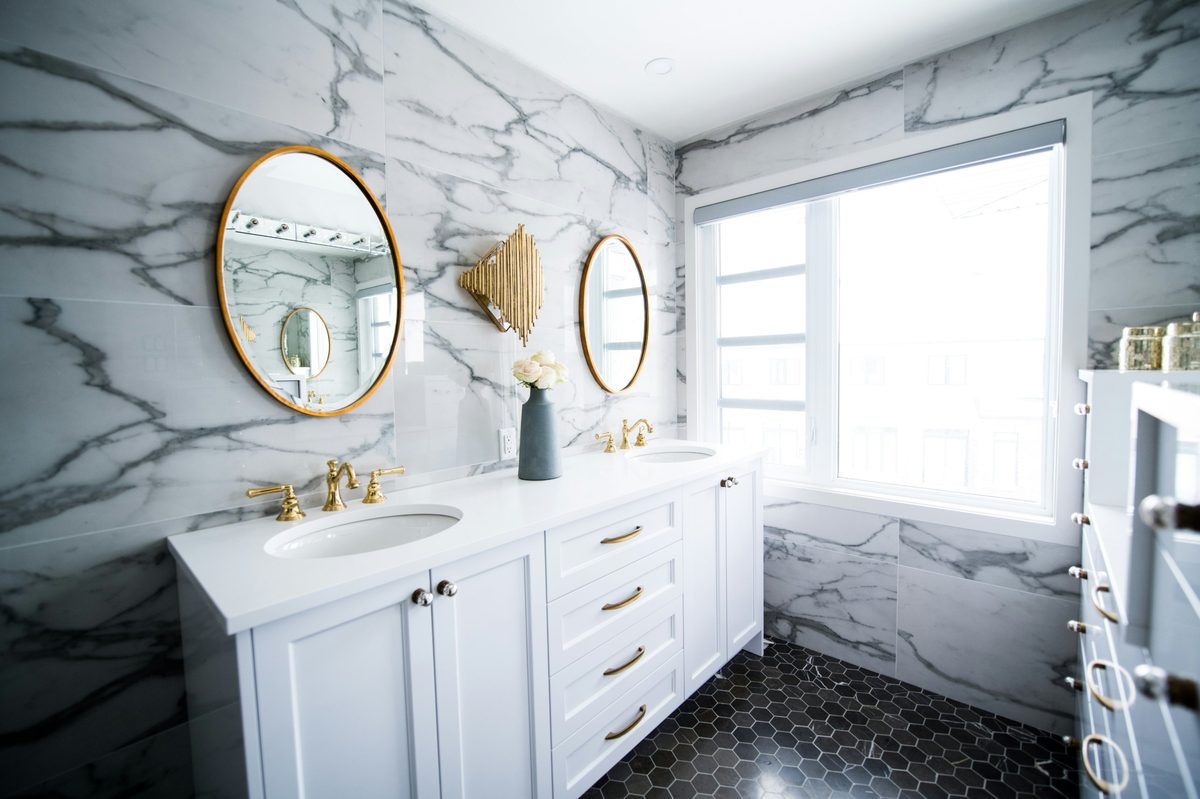 Bathroom with marble tile walls, double vanity and round mirrors